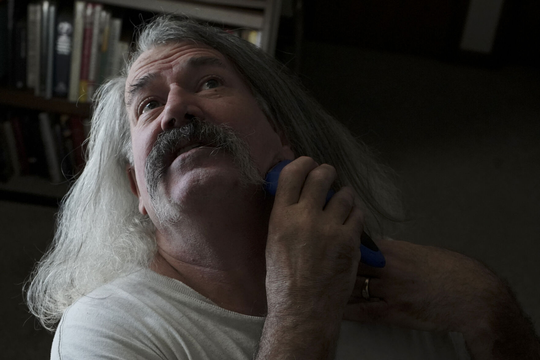 Robert Morrison shaves at his desk before leaving his home